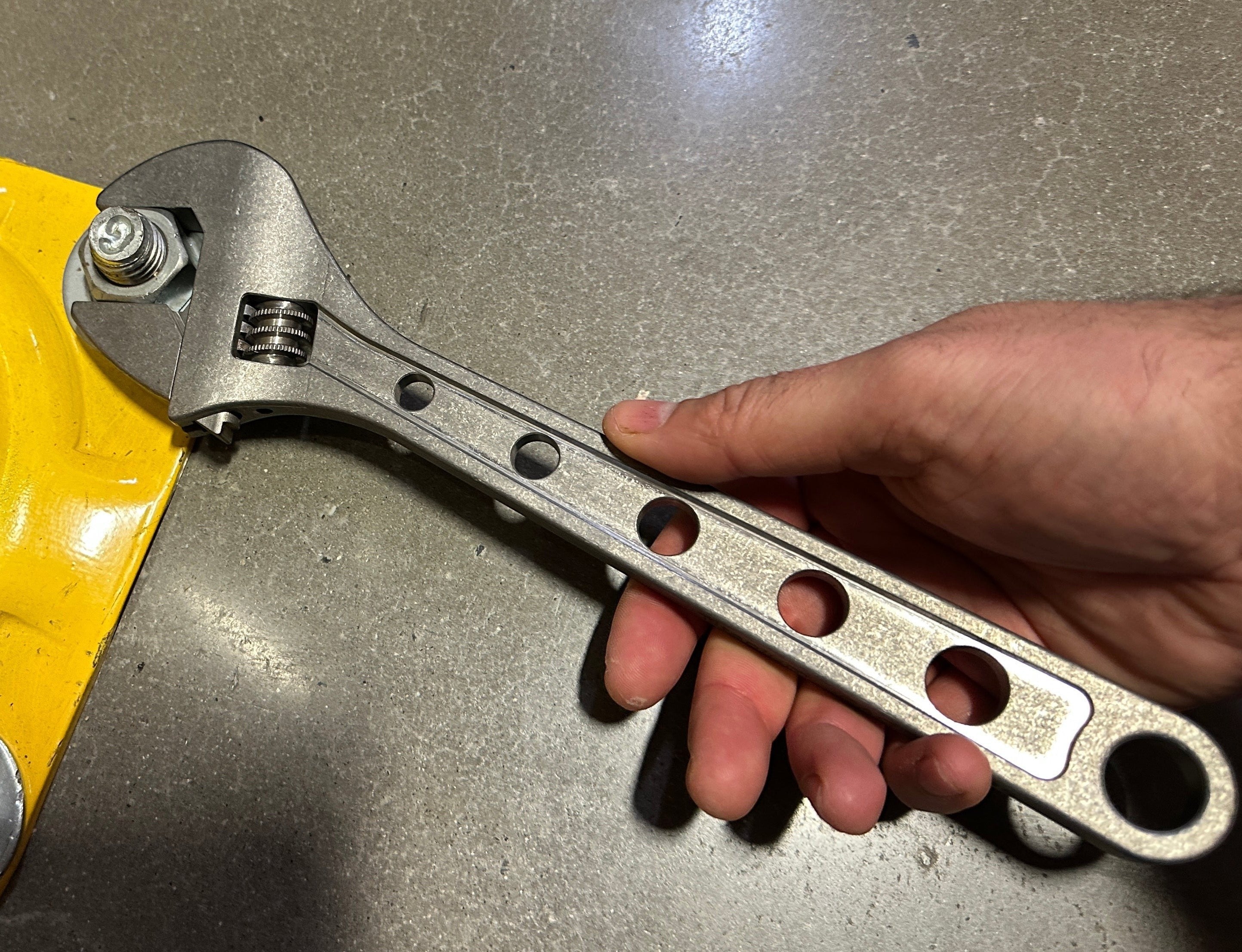 CountyComm 12-inch adjustable wrench made of brushed titanium with 6 tether holes and a matte finish.